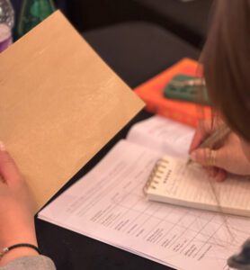 Personne en formation de médiumnité réalisant un exercice de psychométrie avec une enveloppe cachetée et prise de notes